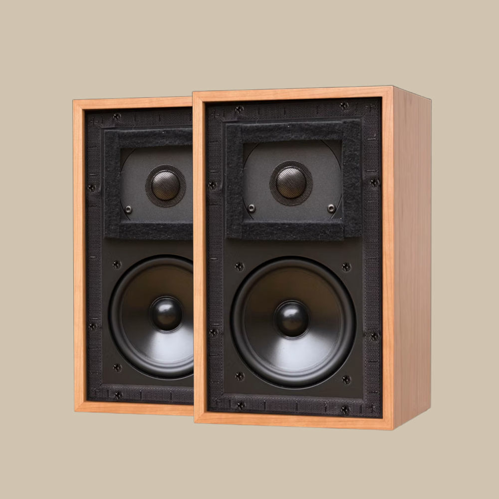 Två klassiska LS3/5A-högtalare i trä, med sina svarta element exponerade, står redo att spela på en enkel beige scen - ren ljudglädje.