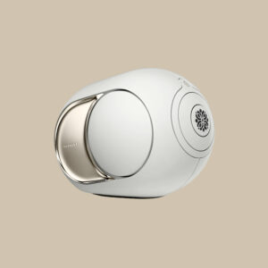 Phantom Ultimate 108 dB, en elegant oval vit högtalare med metalliska vibbar och ett konstnärligt galler, är redo att rocka loss på beige.