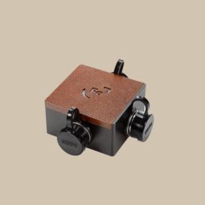 En brun, kubformad Power Splitter, som en förstärkare med "Fe" och "26", har tre runda svarta urtavlor på en beige scen.