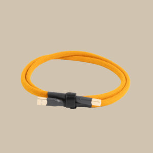 En gul flätad USB-kabel, slingrad som en vinylskiva och hållen av en svart rem, vilar ensam på en slät beige scen.