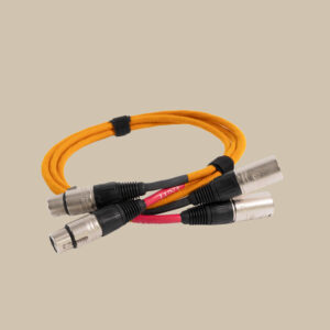 Kraftig orange ljudkabel upprullad, med tre XLR-kontakter i varje ände, fastspänd med svart kardborreband på en beige bakgrund.