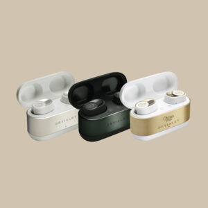 Devialet Gemini II-öronsnäckor i vitt, svart och snyggt guldaccentuerat fodral - redo att leverera rent ljud på en mjuk beige scen.