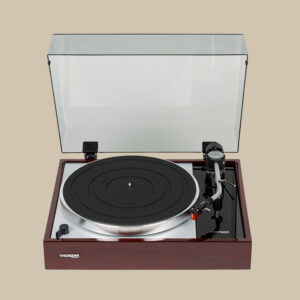 Thorens TD-1500 skivspelare är redo att snurra, med en klassisk träbas och silverplatta som skiner, och tonarmen är placerad över en beige bakgrund.