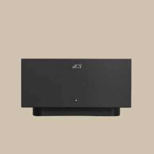 Ett elegant svart Lina Master Clock från DCS står på en beige yta, och dess minimalistiska utseende och enda lampa andas audiofil elegans.
