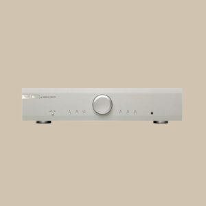 Musical Fidelity M2SI skimrar i silver med en stor central ratt som lockar, flankerad av knappar och ett färdigt hörlursuttag i beige.