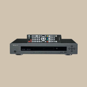 En elegant svart Oppo BDT-103EU Blu-ray-spelare, redo att snurra konsertskivor, med fjärrkontrollen på toppen, mot en beige bakgrund.