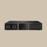 Naim Audio NAC-282, elegant i svart med djärva rattar och en grön logotyp, utlovar rent ljud på en beige scen.