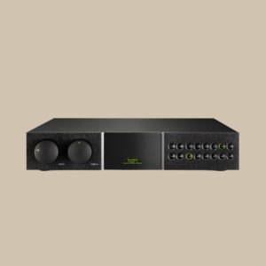 Naim Audio NAC-282, elegant i svart med djärva rattar och en grön logotyp, utlovar rent ljud på en beige scen.