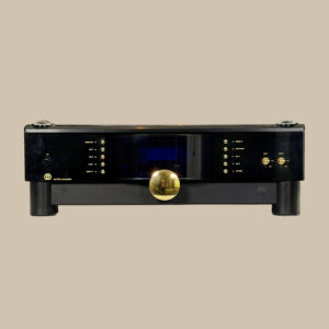 MBL 5011, elegant i svart med en djärv guldknopp och en blå display, utlovar ren ljudlycka mot en enkel beige bakgrund.
