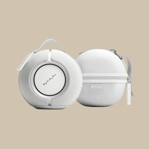 Ett par Mania Exclusive Edition White Mist-högtalare - redo att spela musik - sitter på en beige botten. Den ena har Devialets logotyp, den andra har blixtlås och handtag.
