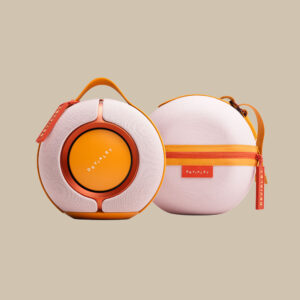 Två Mania White Mist-högtalare i orange och vitt - bärbara jam-maskiner med handtag, Devialet-logotyp och en matchande väska.