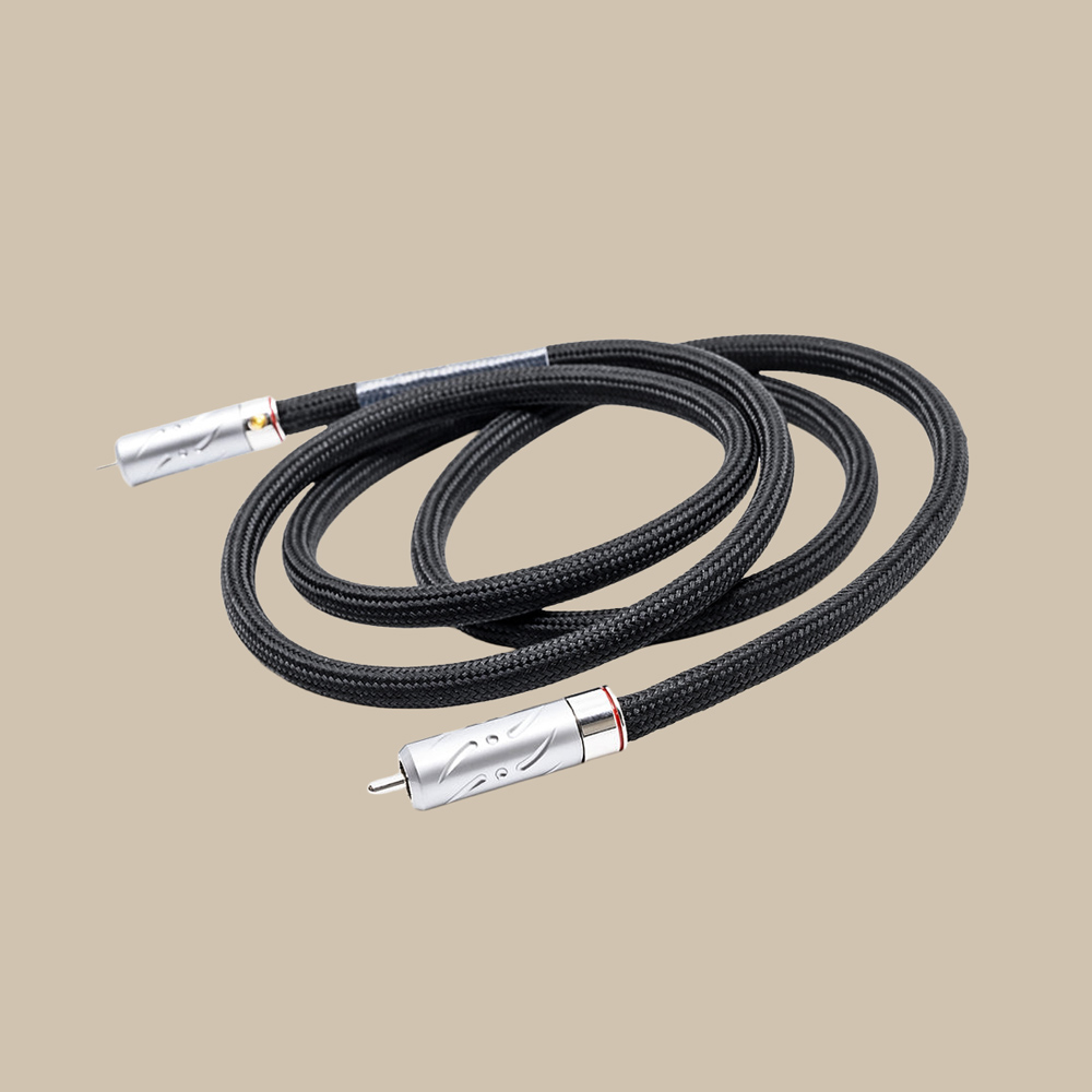 Pachanko Labs Wave SPDIF 1 m är en elegant, svart flätad RCA-kabel med glänsande silverfärgade kontakter, stilfullt upprullad på en beige tråd.